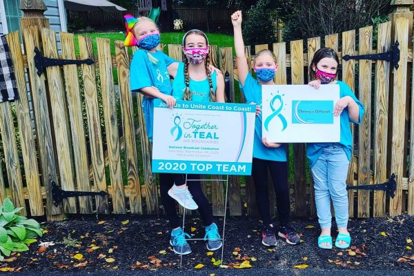 Masked children cheering by a Together in Teal poster as a top fundraising team