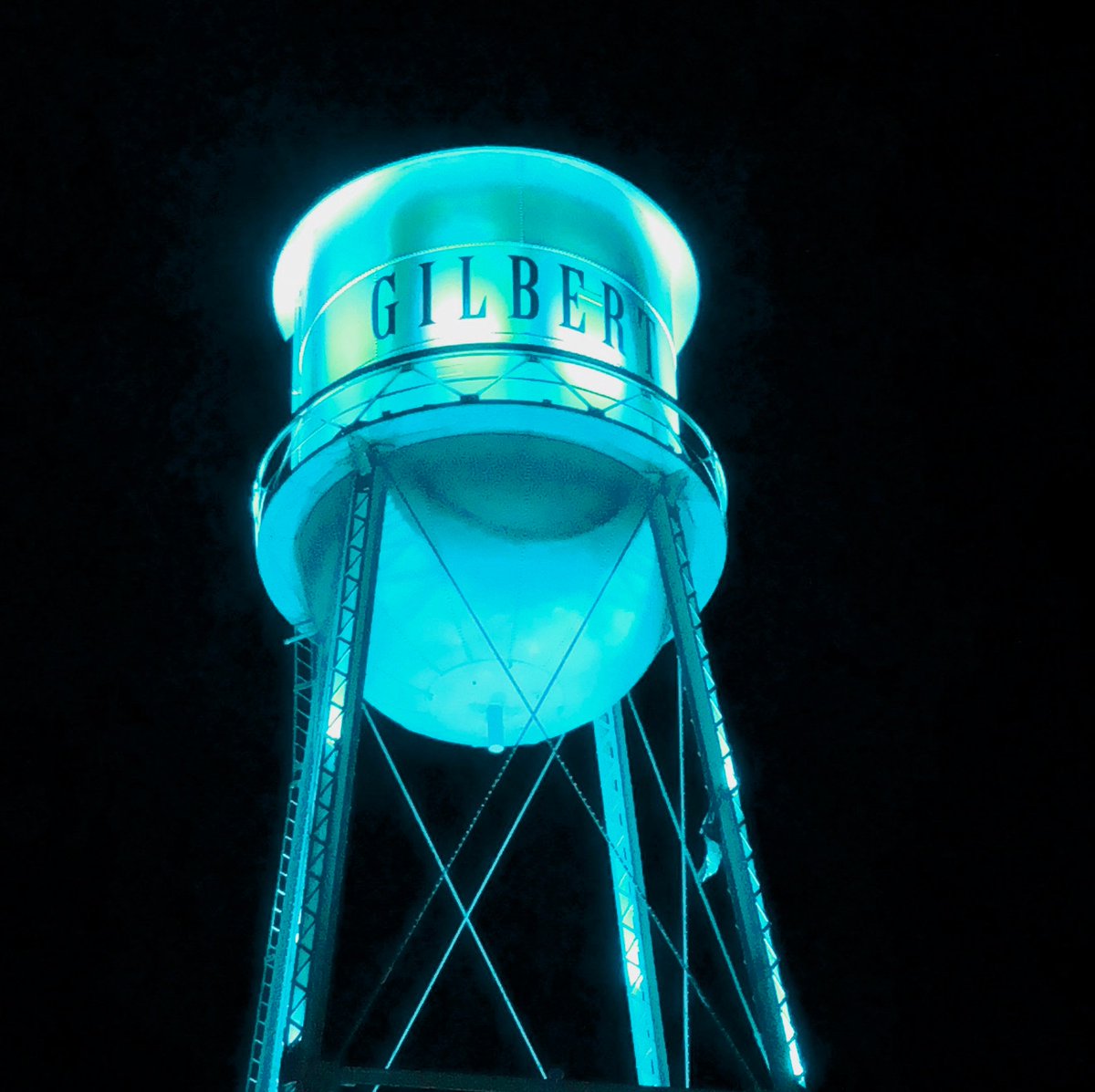 The Gilbert water tower at night, illuminated in teal