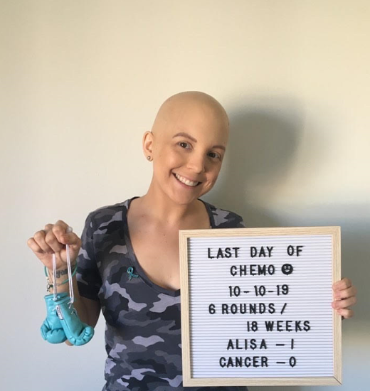 A young ovarian cancer survivor holds a sign celebrating her last day of chemo