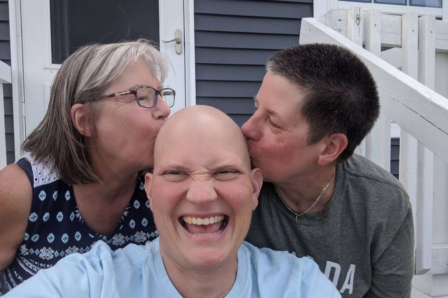 A survivor laughs as two women kiss her bald head