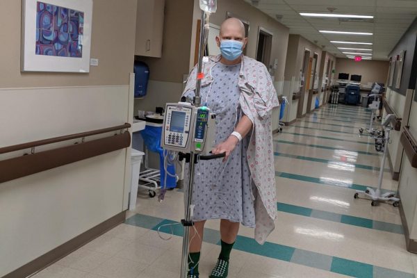 A ovarian cancer patient walks down a hospital corridor with her IV pole