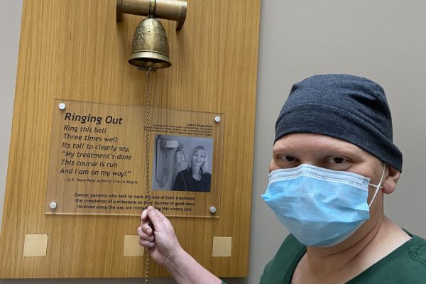 A masked patient rings the bell to celebrate her last chemo